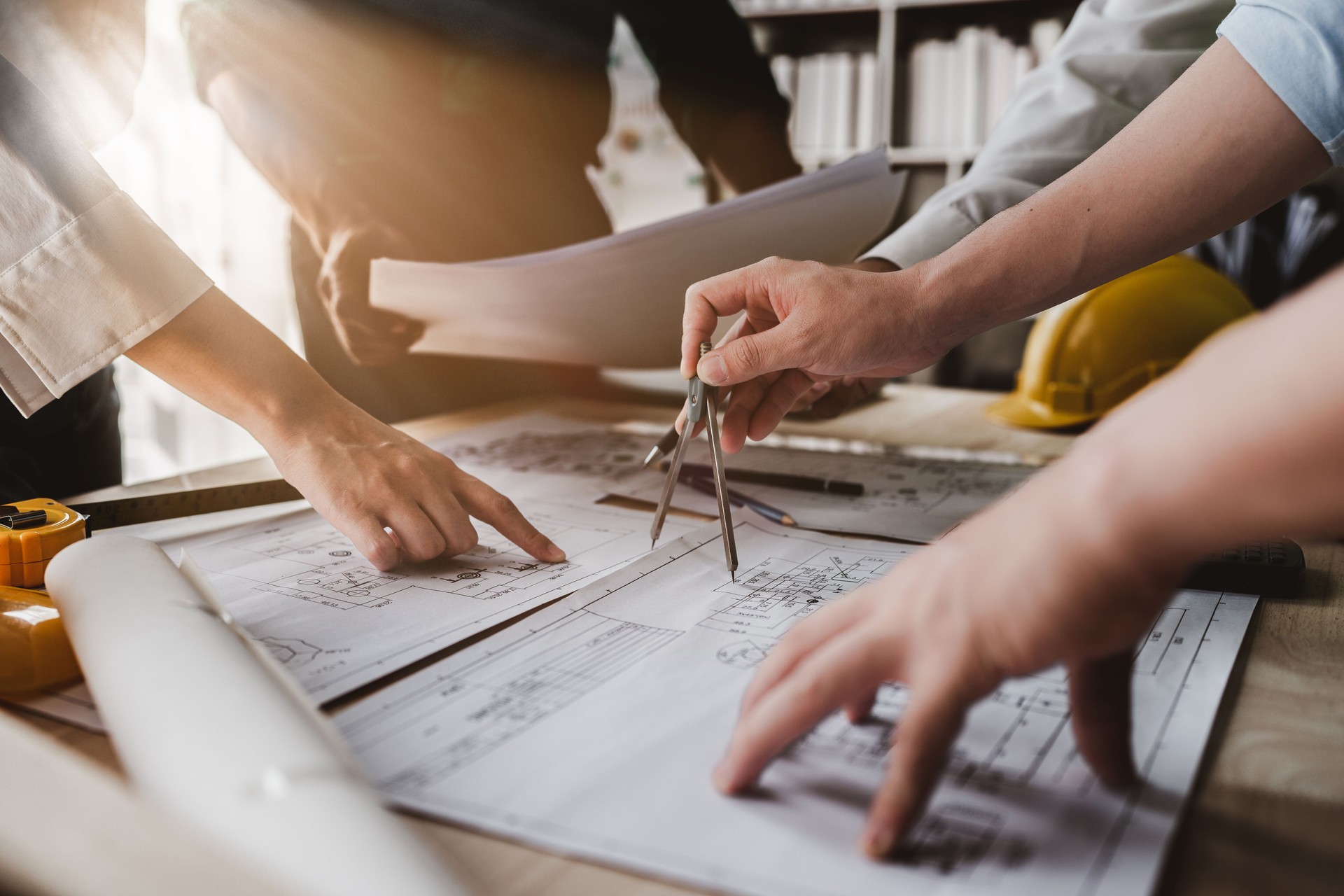 Architect team working with blueprints for architectural plan, engineer sketching a construction project, green energy concept